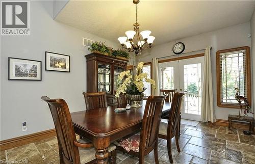 Vaulted ceiling, stone-look tile flooring, double French doors, wood trim, and a chandelier lighting fixture - 915 Briardean Road, Cambridge, ON 