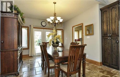 Dining area with stone-look tile flooring, a chandelier, and double French doors - 915 Briardean Road, Cambridge, ON 