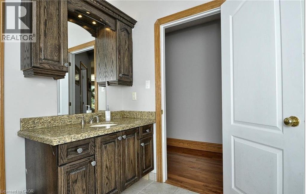 Wood-finish vanity with a stone countertop and an undermount sink - 915 Briardean Road, Cambridge, ON
