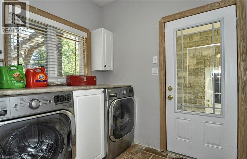 Laundry room featuring a full-light panel door, built-in cabinetry, and wood-trim windows - 915 Briardean Road, Cambridge, ON