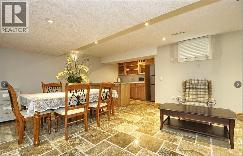 Recessed lighting, wood-finish cabinetry, built-in shelving, stone tile flooring, and a large window with blinds - 915 Briardean Road, Cambridge, ON