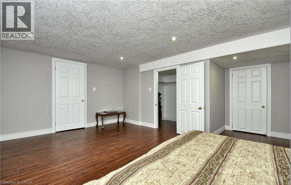 Recessed lighting illuminates wood-finish flooring, white paneled doors, and light gray walls - 915 Briardean Road, Cambridge, ON