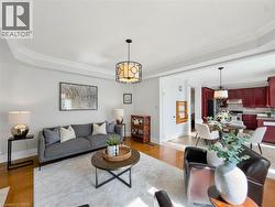 Hardwood flooring, crown molding, a decorative ceiling light fixture, and an open concept dining area with a kitchen featuring custom cabinetry -
