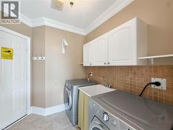Crown molding, white upper cabinetry, square tile backsplash, utility sink, and tile flooring -
