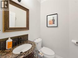 Granite countertop, under-mount sink, dark wood vanity, decorative tile backsplash, and an ornate framed mirror -