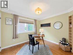 Light-filled room featuring wood-finish flooring, crown molding, a window with blinds, and built-in shelving -