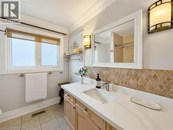 White-framed window with roller shades, light wood-finish vanity with an integrated rectangular sink, white countertop, and diamond-patterned tiled backsplash -