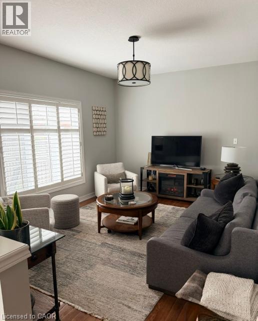 Vaulted ceiling featuring a decorative semi-flush mount light fixture, large windows with plantation shutters, and wood-finish flooring - 5383 Haldimand Crescent, Burlington, ON