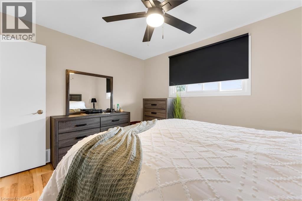 Bedroom featuring a ceiling fan with light, a window with a roller shade, and light-colored walls - 7506 Jubilee Drive, Niagara Falls, ON