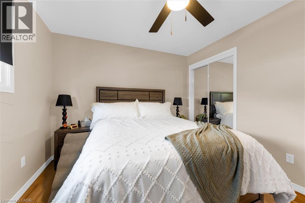 This room features wood flooring, a ceiling fan, and mirrored closet doors - 7506 Jubilee Drive, Niagara Falls, ON