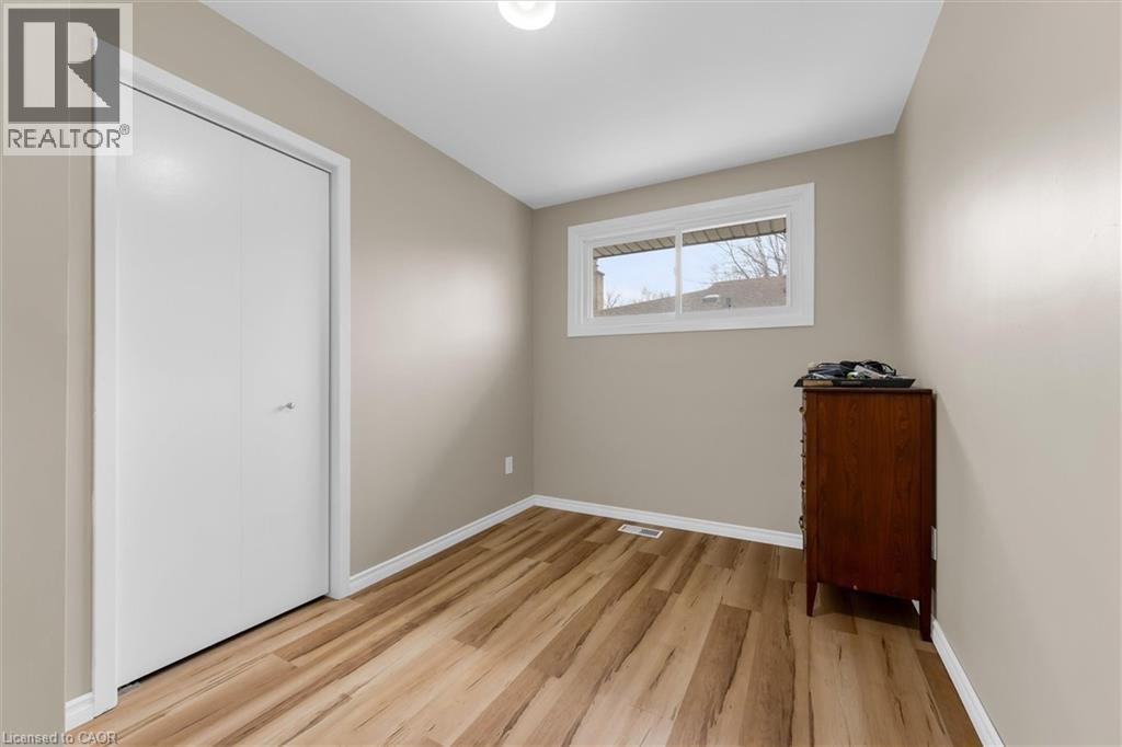 This room features light-colored walls, wide plank flooring, and a window with white trim - 7506 Jubilee Drive, Niagara Falls, ON