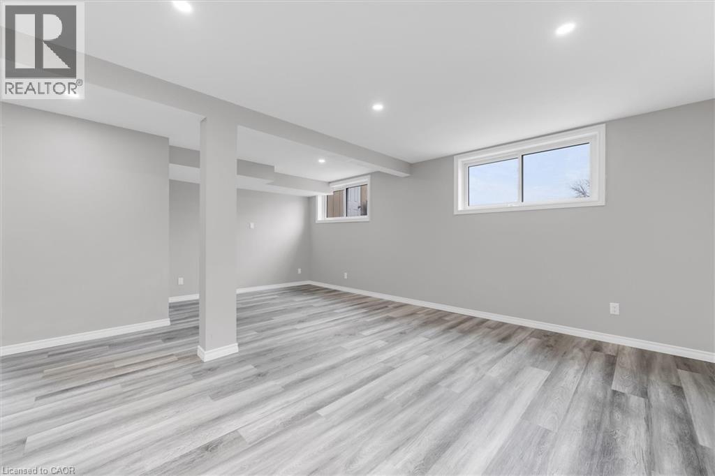 Spacious room with light gray walls, gray wood-style flooring, and recessed lighting - 7506 Jubilee Drive, Niagara Falls, ON