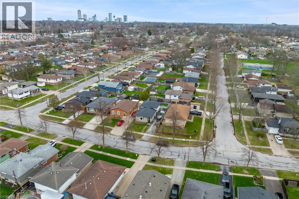 Aerial view showcasing the residential neighbourhood with a variety of homes, tree-lined streets, and a distant city skyline - 7506 Jubilee Drive, Niagara Falls, ON