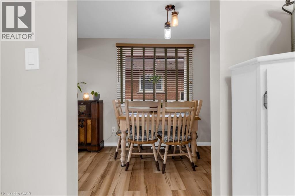 The dining area features wood-look flooring and a window with blinds - 7506 Jubilee Drive, Niagara Falls, ON