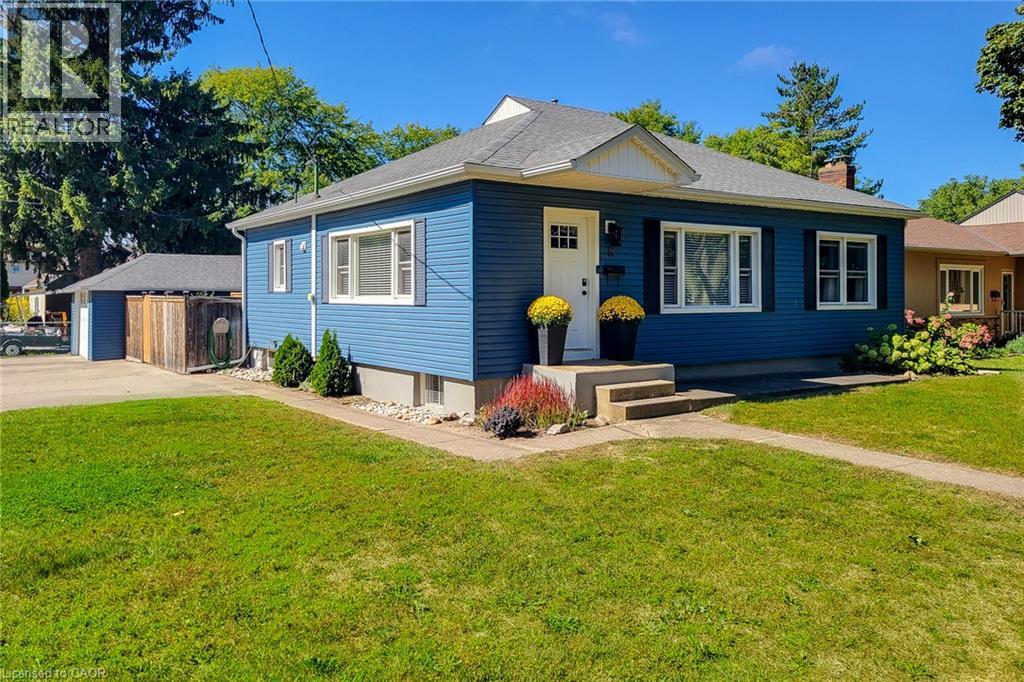 Blue siding exterior with white window trim, dark shutters, a front entry with a white door, concrete steps, and an attached garage - 19 Thorndale Avenue, St. Catharines, ON