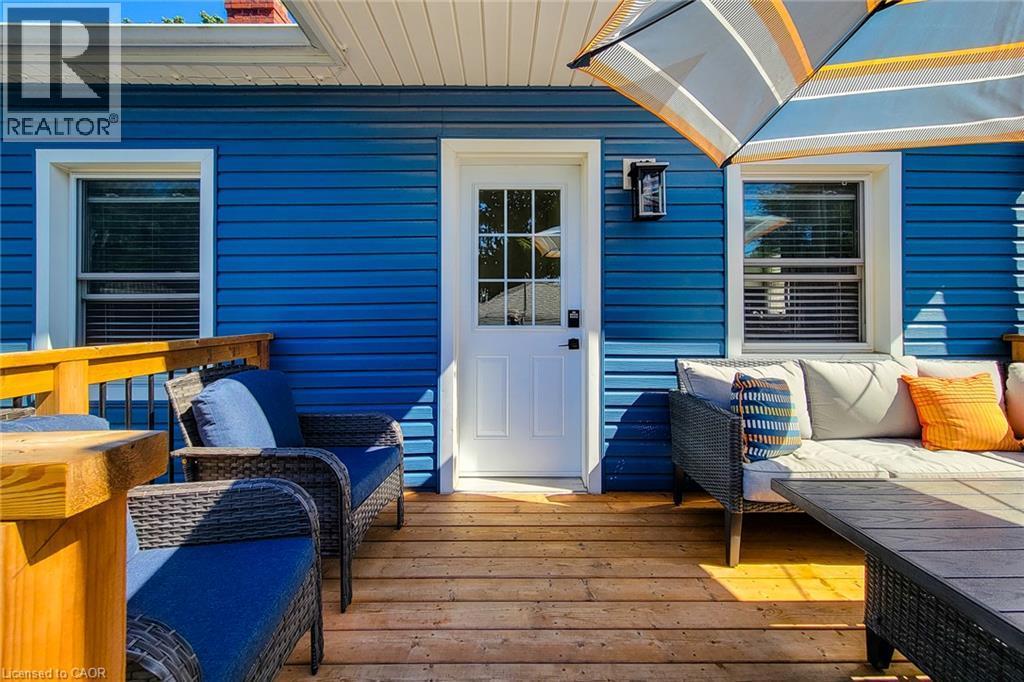 Wood deck with wood railing, blue siding, white exterior door with glass panes, and exterior wall lantern - 19 Thorndale Avenue, St. Catharines, ON