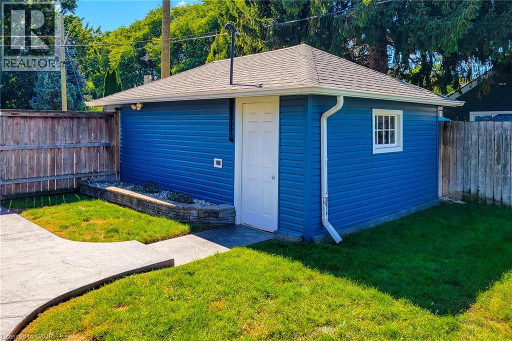 Detached outbuilding with blue siding, a white entry door, and a white-framed window - 19 Thorndale Avenue, St. Catharines, ON