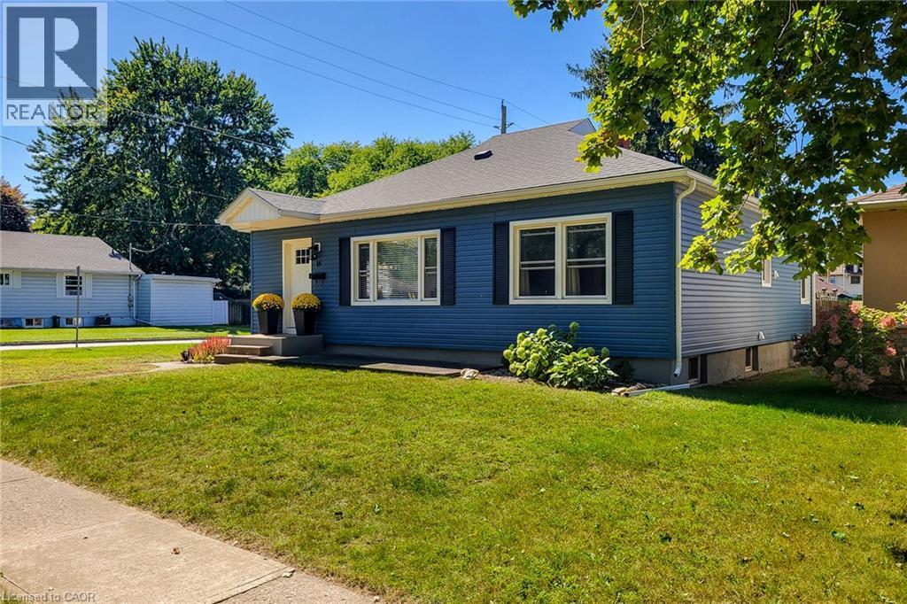 Blue siding exterior with a dark shingle roof, white trim windows, and a concrete pathway leading to the entrance - 19 Thorndale Avenue, St. Catharines, ON