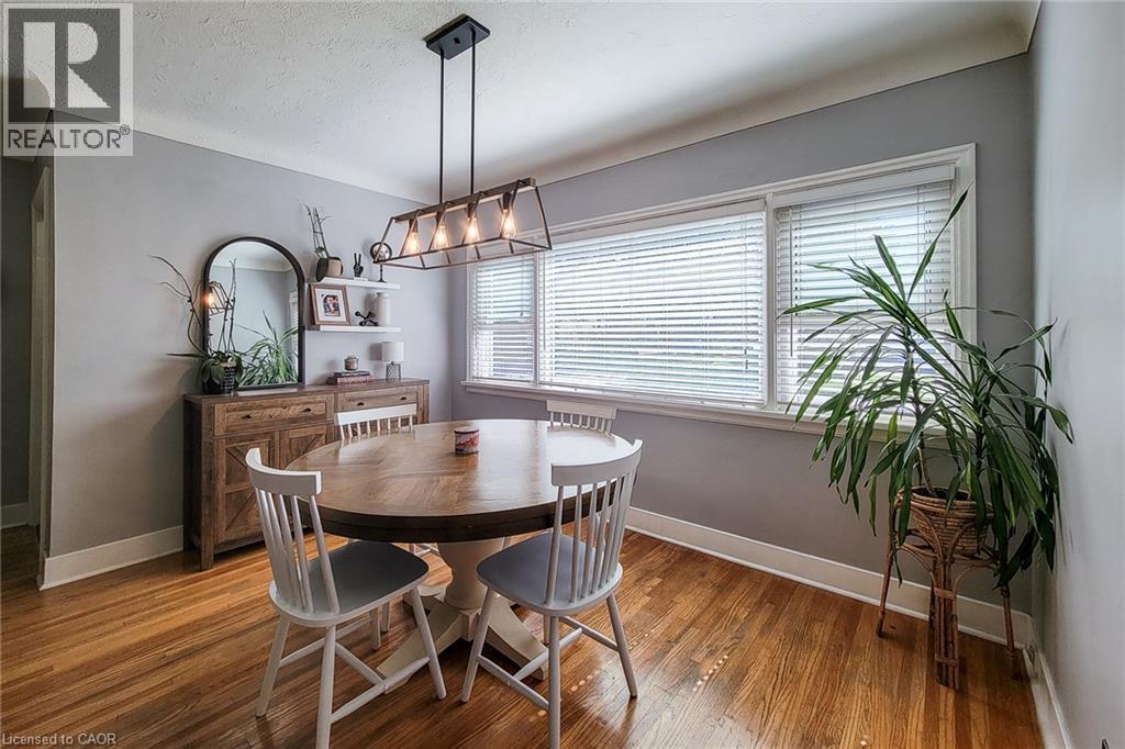 Hardwood flooring, multiple windows with blinds, built-in shelving, and a prominent linear chandelier - 19 Thorndale Avenue, St. Catharines, ON