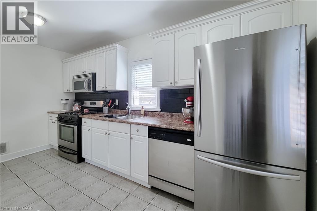 White cabinetry, stainless steel appliances, tiled flooring, and a window with blinds - 19 Thorndale Avenue, St. Catharines, ON