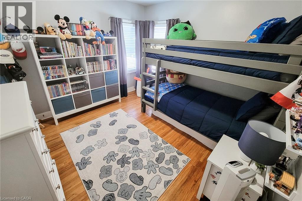 Wood-finish flooring with white baseboards, a built-in bunk bed, and a wall-mounted shelving unit - 19 Thorndale Avenue, St. Catharines, ON