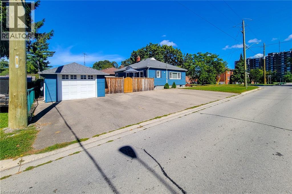 Detached garage with white overhead door, wood fencing, and a blue exterior - 19 Thorndale Avenue, St. Catharines, ON