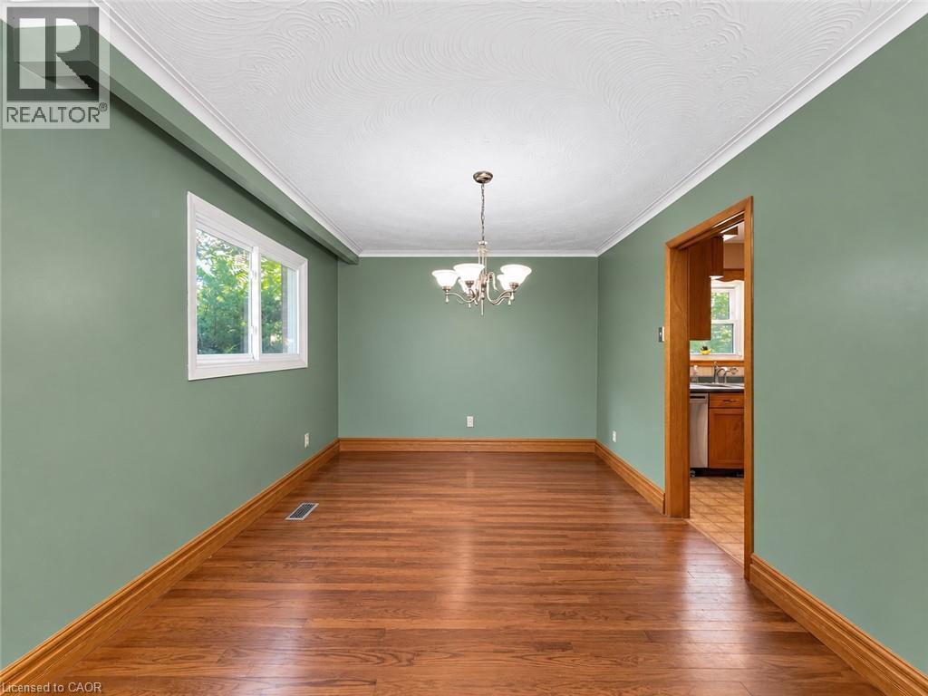 Hardwood flooring with wood trim, white crown molding, and a chandelier lighting fixture - 2490 Yarmouth Crescent, Oakville, ON