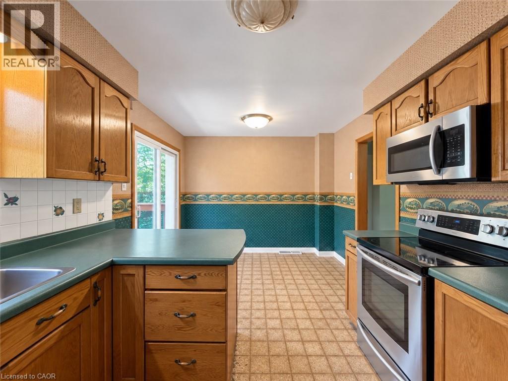 Kitchen featuring oak cabinetry, stainless steel appliances, a built-in microwave, and a glass-top range - 2490 Yarmouth Crescent, Oakville, ON