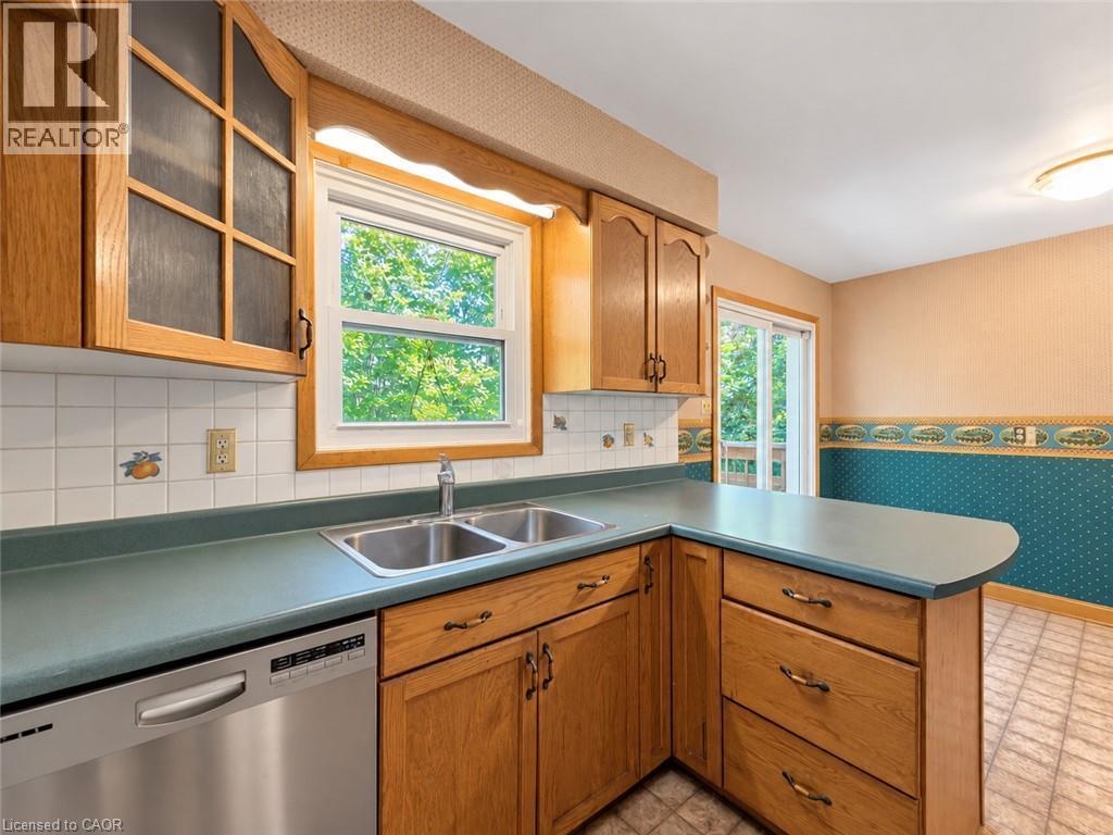 Wood-finish cabinetry, stainless steel dishwasher, double basin sink, and a sliding glass door - 2490 Yarmouth Crescent, Oakville, ON