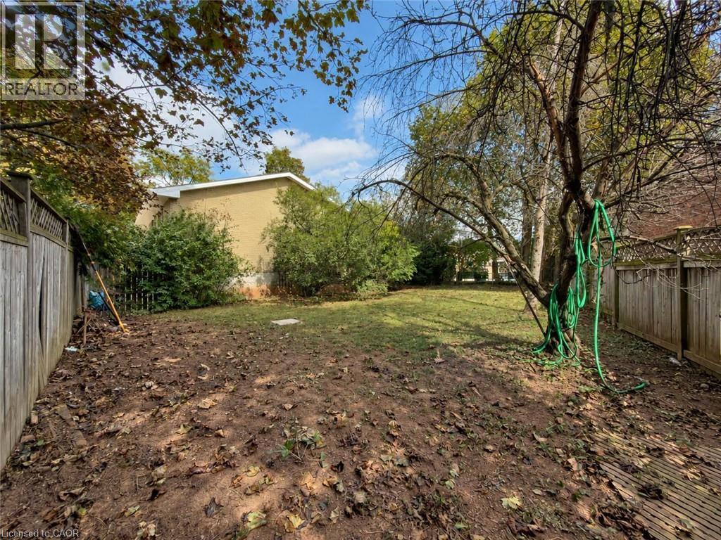 Spacious backyard featuring a substantial mature tree, partial wood fencing, and a partial brick exterior - 2490 Yarmouth Crescent, Oakville, ON