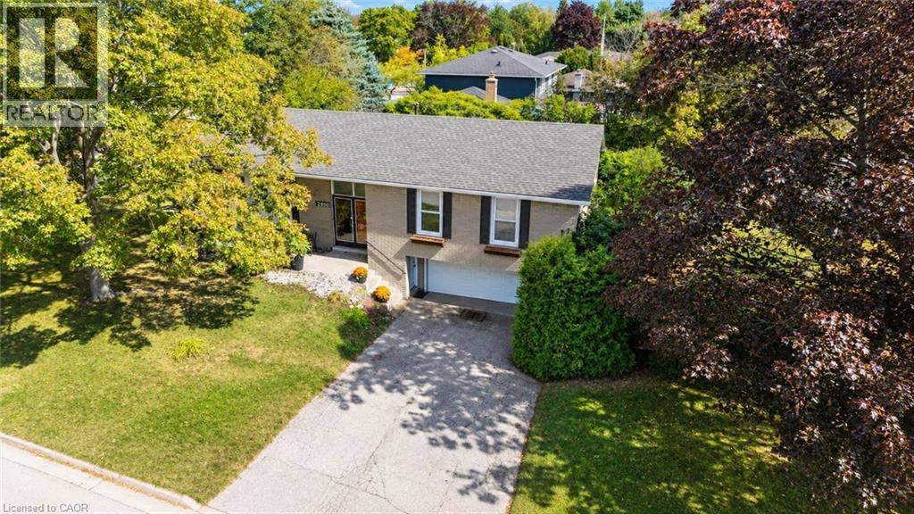 Brick exterior with a gray shingle roof, integrated garage, concrete driveway, and mature landscaping - 2490 Yarmouth Crescent, Oakville, ON