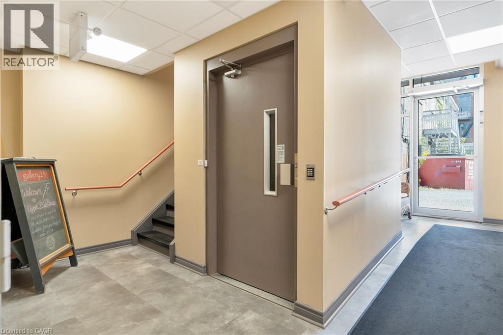 Secured entry door with keypad access, commercial-grade flooring, staircase with wood handrail, and recessed ceiling lighting - 23 Market Street W, Port Dover, ON