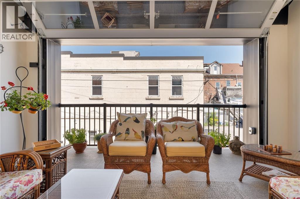 Outdoor patio featuring a black metal railing and a glass paneled overhead door mechanism - 23 Market Street W, Port Dover, ON