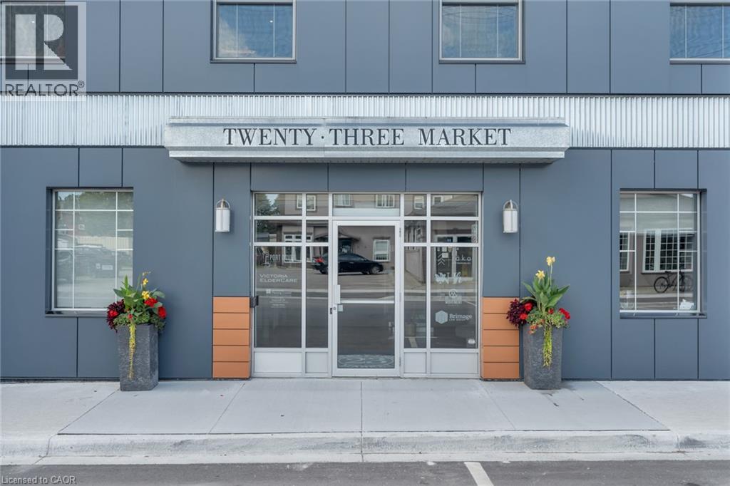 Modern building facade with gray paneling, prominent ""TWENTY-THREE MARKET"" signage, and large glass entry doors - 23 Market Street W, Port Dover, ON