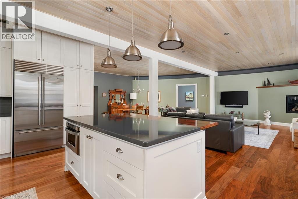 Kitchen island with a dark countertop and built-in microwave, complemented by white cabinetry and stainless steel refrigerator - 23 Market Street W, Port Dover, ON