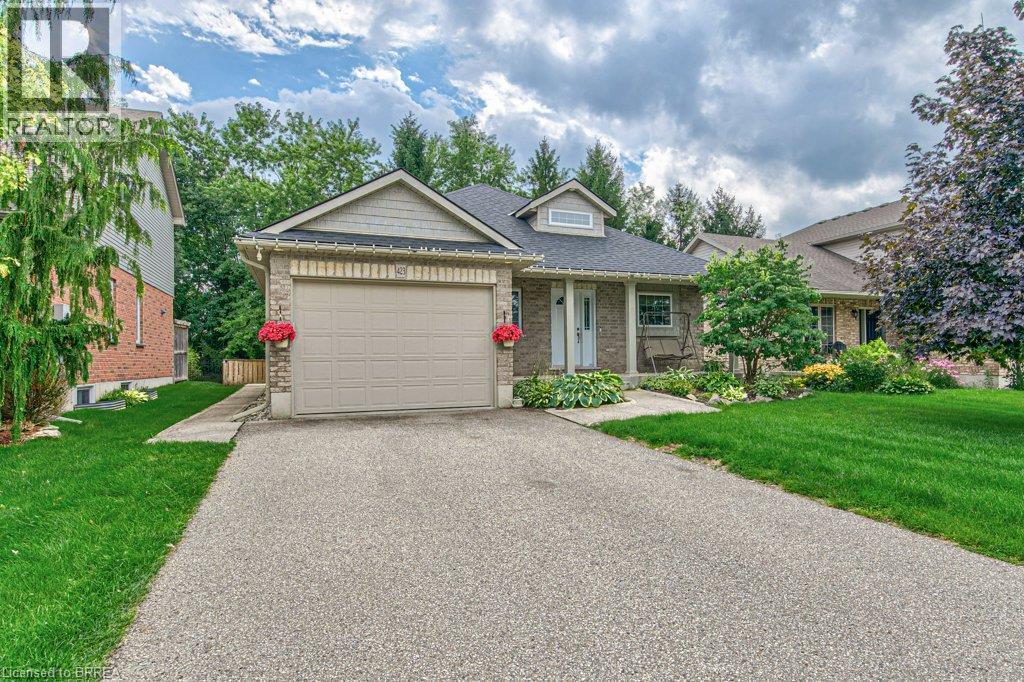 Brick and siding exterior featuring a single-car garage, dormer window, and mature landscaping - 423 Poldon Drive, Norwich, ON