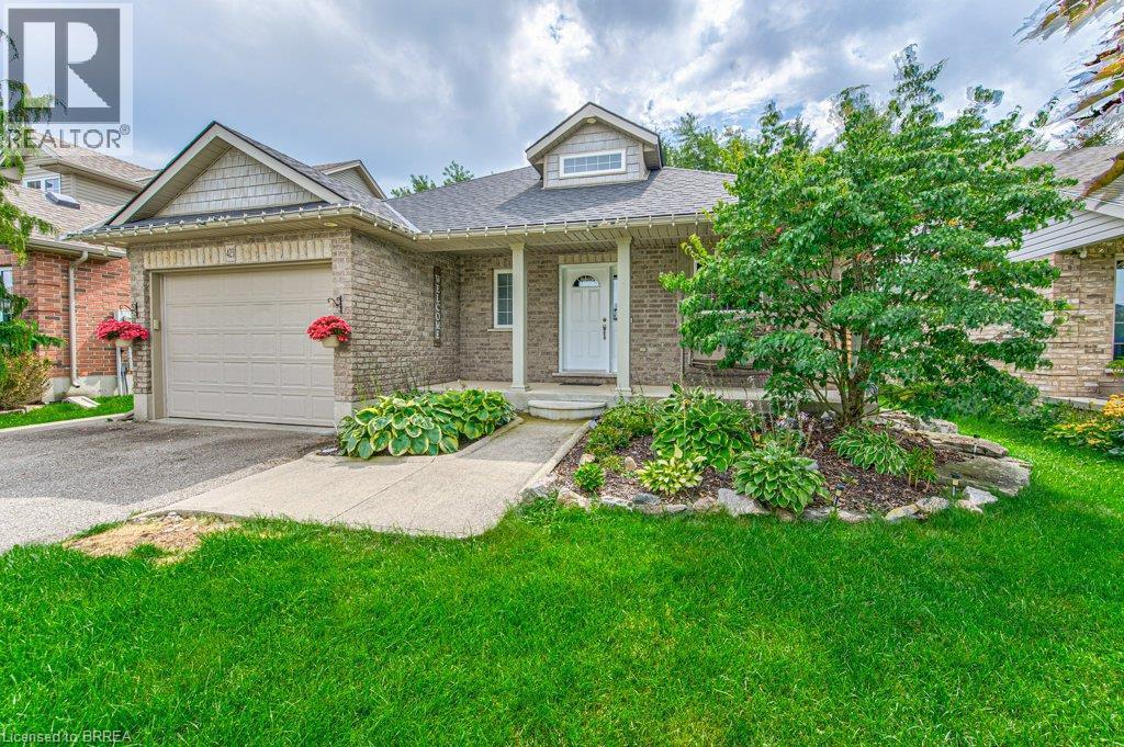 Brick exterior with a peaked roofline, front porch, and an attached garage with a paved driveway - 423 Poldon Drive, Norwich, ON