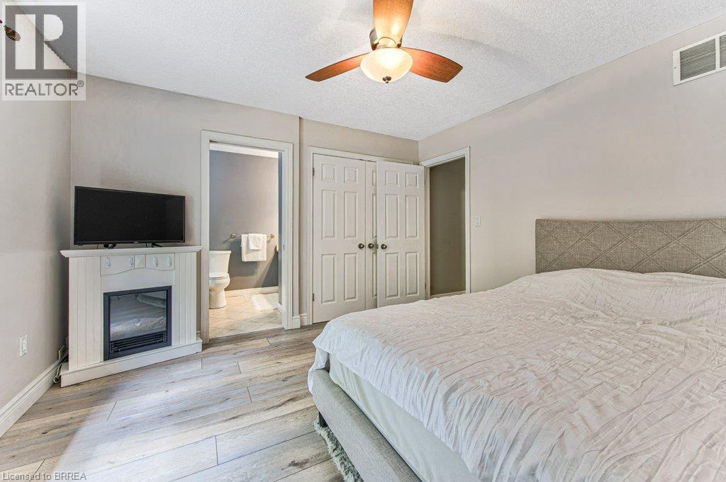 Wood-finish flooring, ceiling fan, white paneled doors, and a decorative electric fireplace - 423 Poldon Drive, Norwich, ON