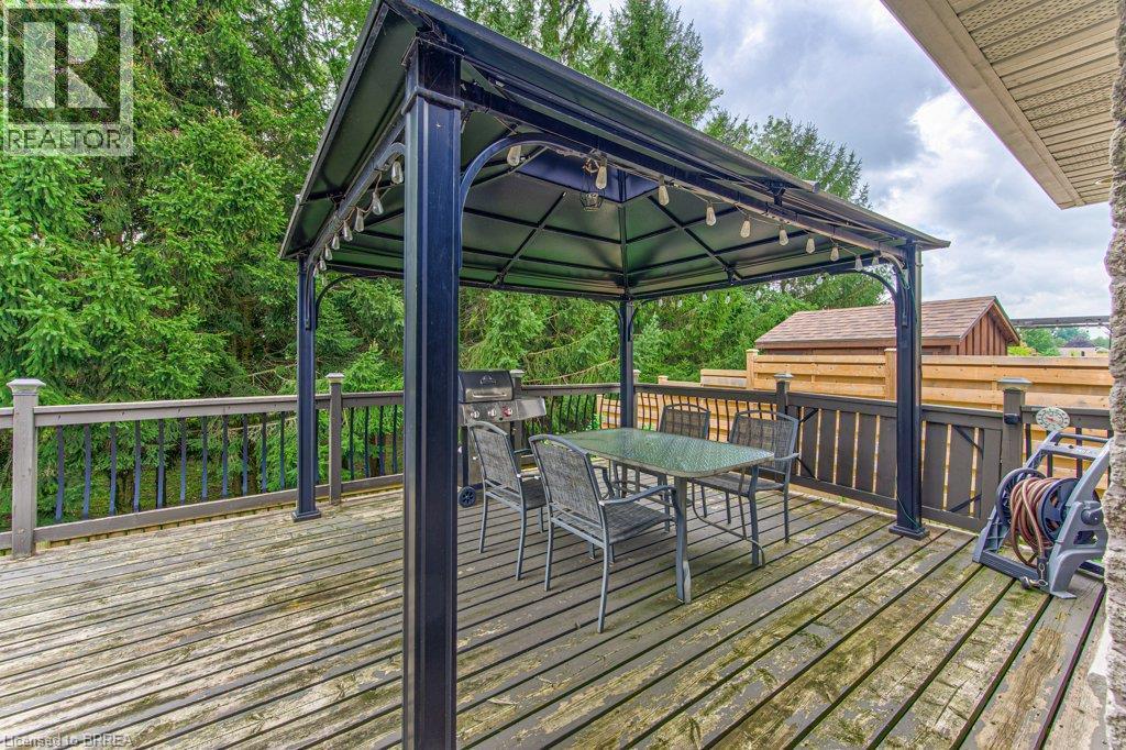 Expansive wooden deck with a built-in gazebo, featuring an attached string lighting system and a privacy fence - 423 Poldon Drive, Norwich, ON