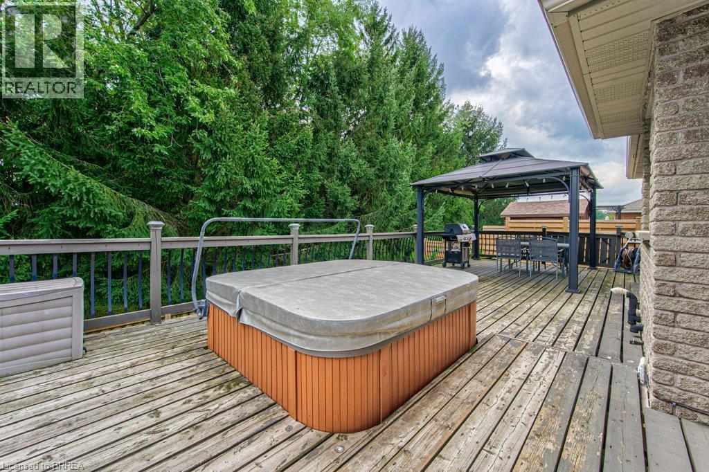 Expansive wood deck featuring a covered hot tub, a detached gazebo, and a brick exterior - 423 Poldon Drive, Norwich, ON