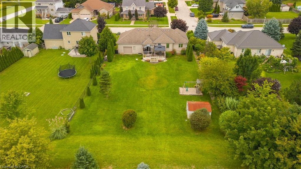 Expansive lot featuring a large lawn, mature trees, and a detached storage shed - 515 Woodward Drive, Mount Brydges, ON