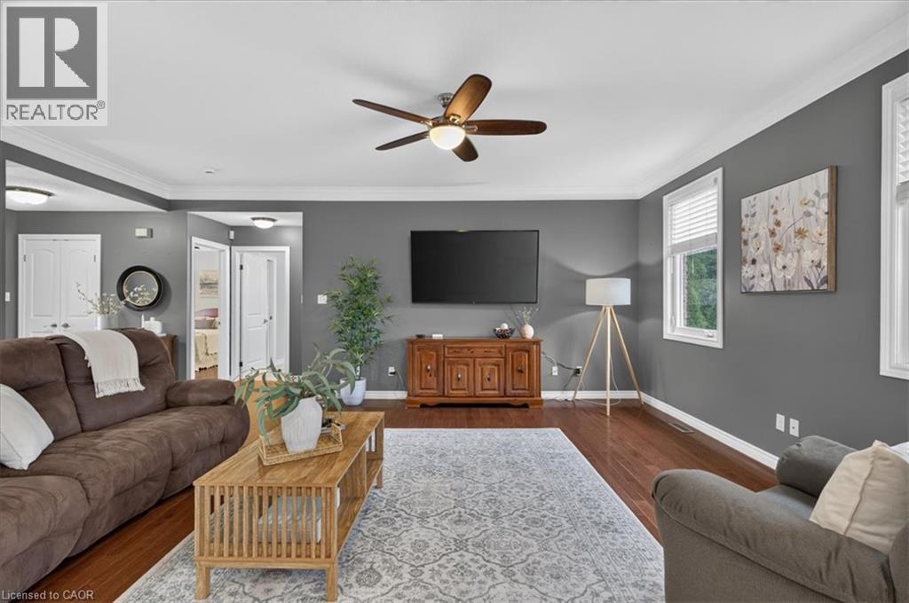 Hardwood flooring, painted walls, crown molding, ceiling fan with integrated lighting, and multiple windows with blinds - 515 Woodward Drive, Mount Brydges, ON