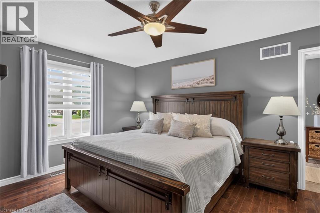 Wood-finish flooring, ceiling fan with integrated lighting, window with horizontal blinds, gray painted walls, and white trim - 515 Woodward Drive, Mount Brydges, ON