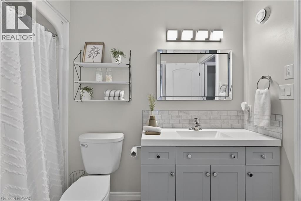 Light gray vanity with ample storage, white countertop, and subway tile backsplash - 515 Woodward Drive, Mount Brydges, ON