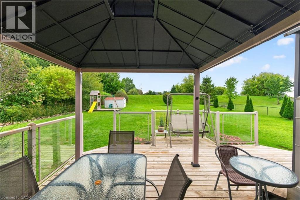 Expansive outdoor deck with a permanent gazebo structure, wood-finish flooring, and clear panel railings - 515 Woodward Drive, Mount Brydges, ON