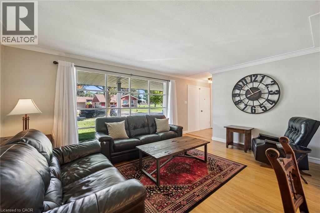 Spacious living area featuring light wood-finish flooring, a large picture window, and crown molding - 35 Crosby Drive, Kitchener, ON