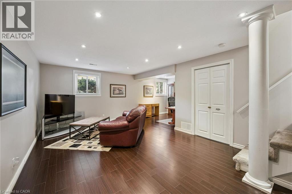 Recessed lighting, dark wood-finish flooring, white bi-fold doors, white window trim, and a decorative column - 35 Crosby Drive, Kitchener, ON