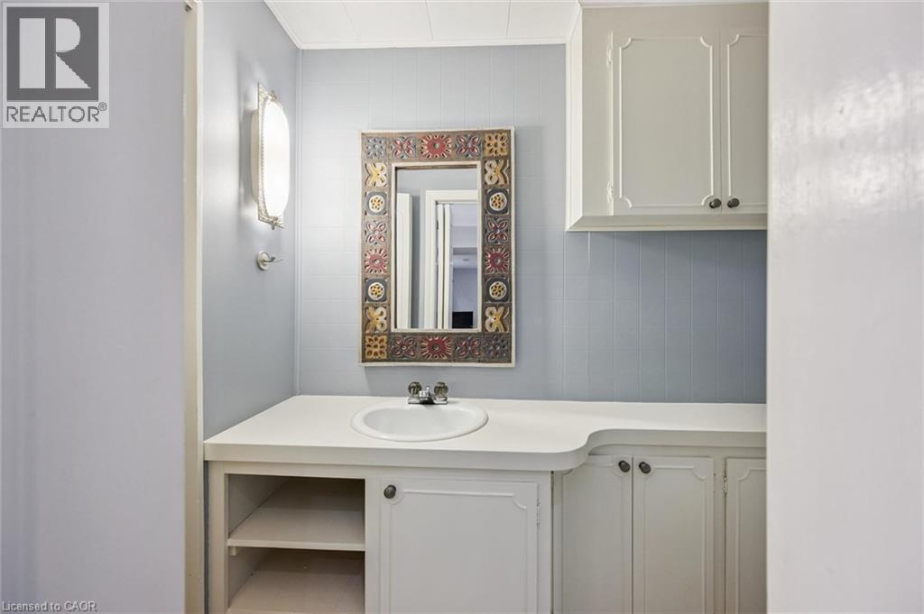 Built-in vanity with integrated sink, white countertop, white cabinetry with dark hardware, built-in shelving, and wall-mounted lighting - 35 Crosby Drive, Kitchener, ON