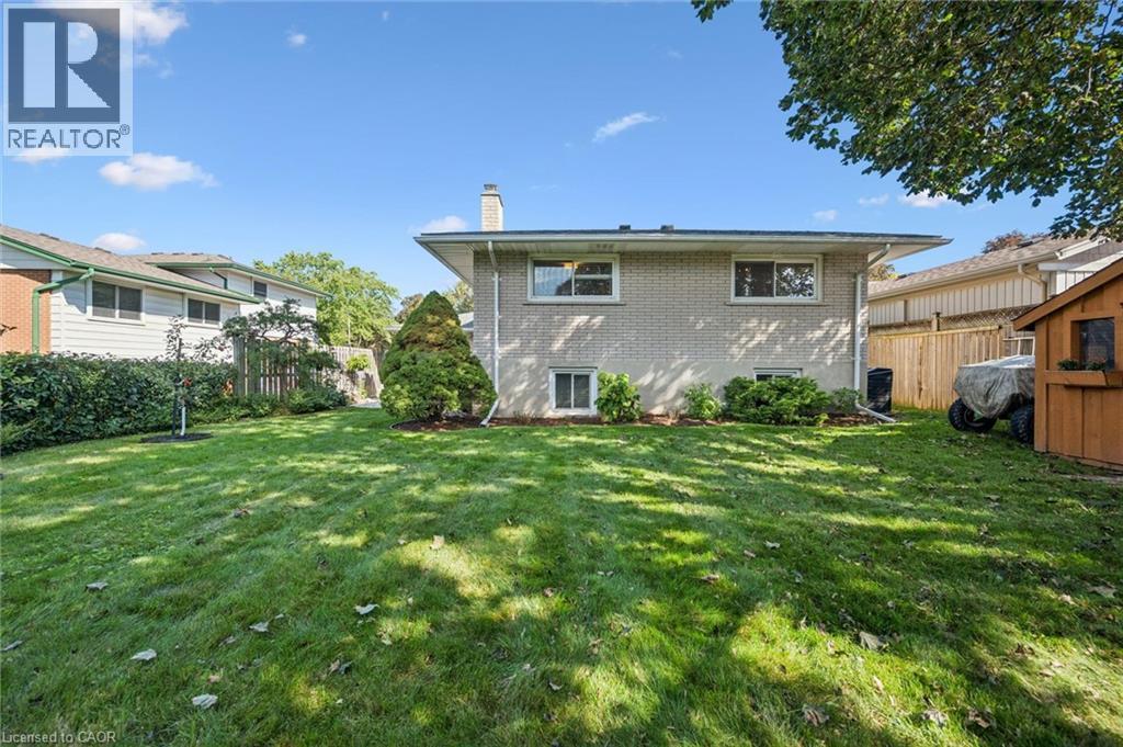 Expansive lawn area, brick exterior, multiple windows, mature trees, and a storage shed - 35 Crosby Drive, Kitchener, ON