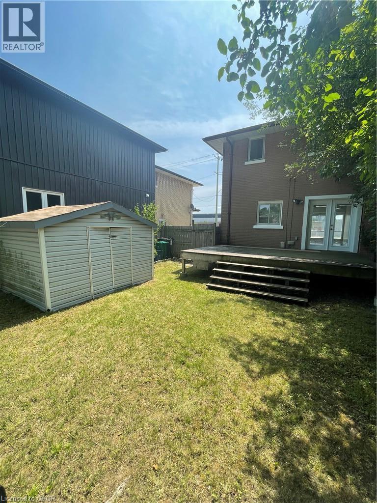 Spacious backyard with a wood deck, multiple steps, and a storage shed - 124 Avalon Place, Kitchener, ON